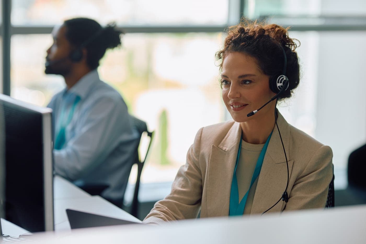 A smiling customer-service representative on a call from her desk